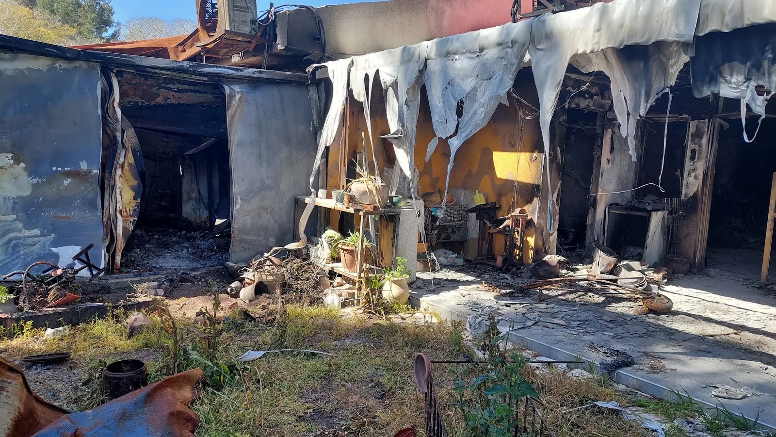 Fachada de una vivienda quemada, con ventanas y paredes dañadas.