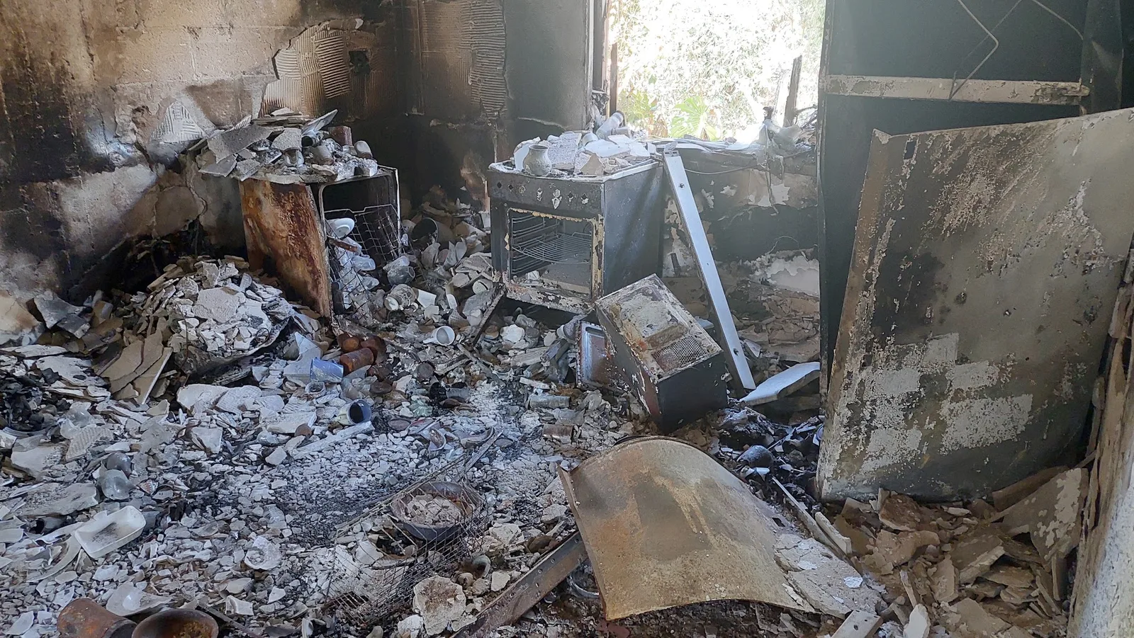 Interior de una vivienda destruida, cubierto de escombros y objetos quemados.